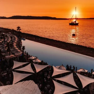 The sun setting over the Mediterranean at Cafe Del Mar Malta, casting golden reflections on the water.