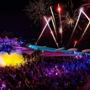 A dazzling fireworks display lighting up the night sky above Cafe Del Mar Malta, with a lively crowd below.