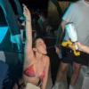A woman sipping champagne while holding a champagne gun at a pool party at Cafe Del Mar Malta.