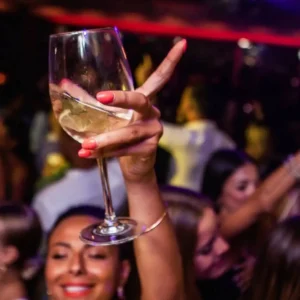 Partygoer raising her glass in celebration at Twenty Two Malta, a symbol of the vibrant nightlife experience the venue offers.