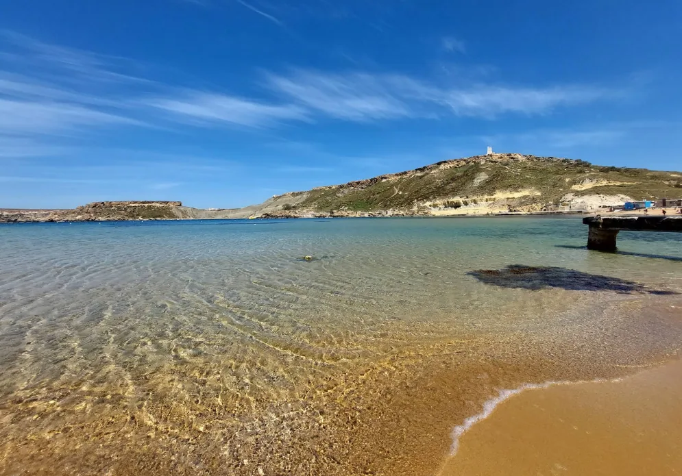 Gnejna Bay beach Malta – baia sabbiosa con acqua blu calma circondata da scogliere calcaree