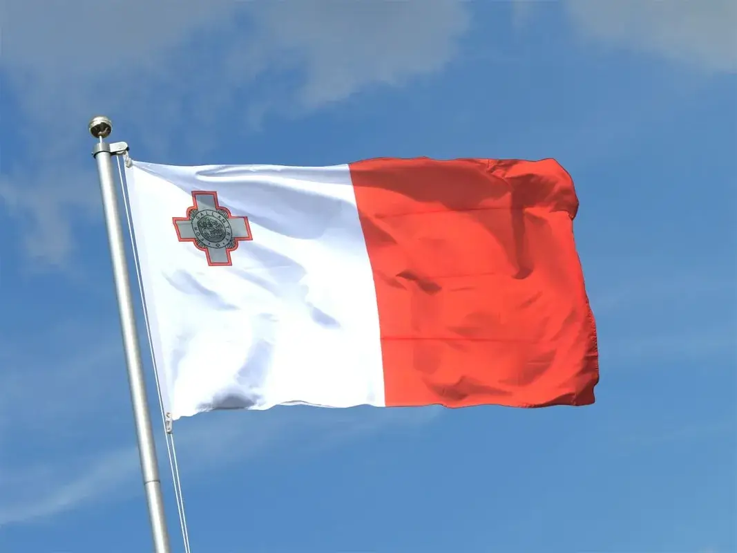 Maltese flag flying in the wind showing white and red stripes with the George Cross in the upper left corner