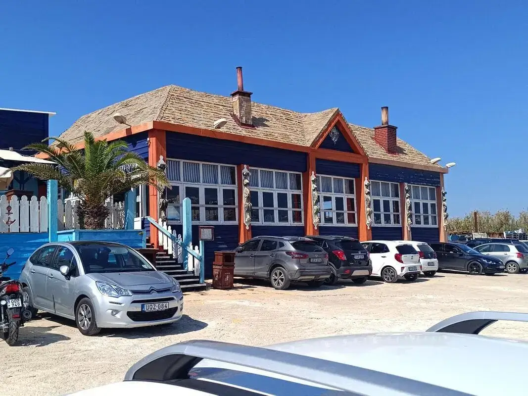 Parcheggio e ingresso Popeye Village Malta Anchor Bay Mellieha Parcheggio con auto e edificio colorato blu e arancione all\'ingresso del Popeye Village Malta vicino ad Anchor Bay Mellieha Malta