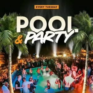 Night view of the illuminated open-air rooftop pool party at Gianpula Village in Malta with Mdina visible in the background.