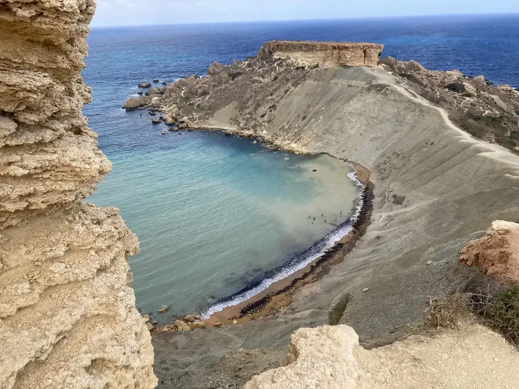 Qarraba Bay hidden cove between dramatic clay cliffs with turquoise water aerial view in Malta