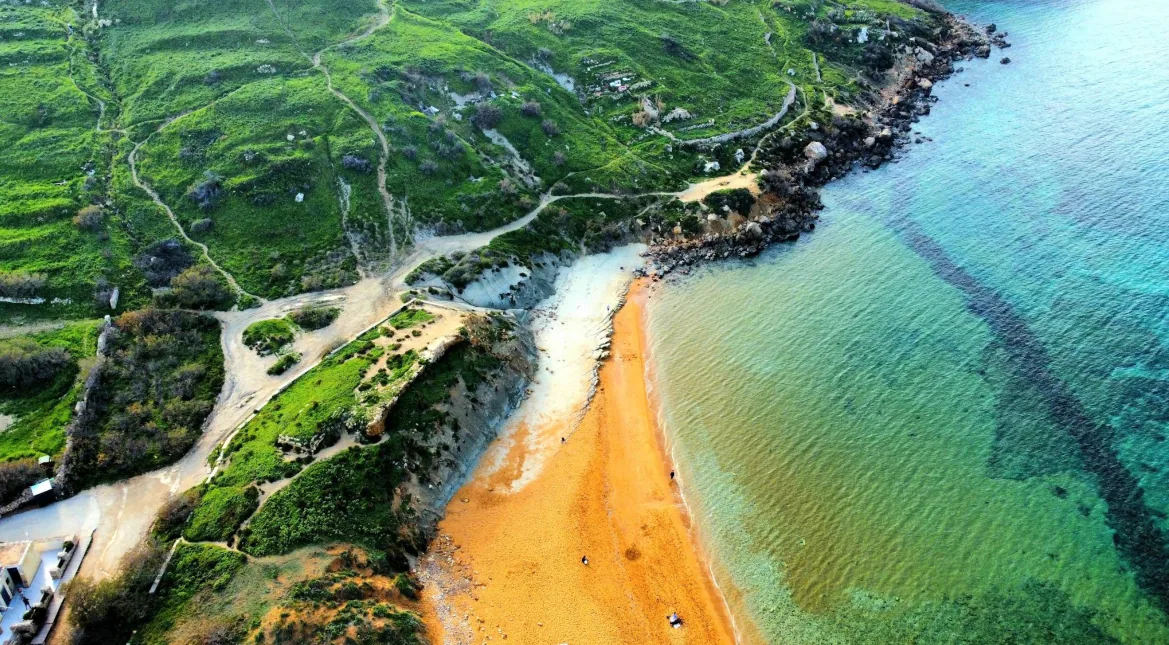 vista aerea Ramla Bay Gozo sabbia rossa arancione valle verdeggiante