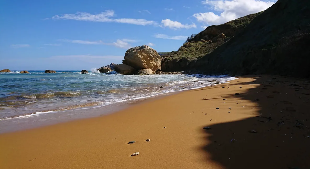 San Blas Bay spiaggia isolata sabbia rossa arancione Gozo rocce onde dolci