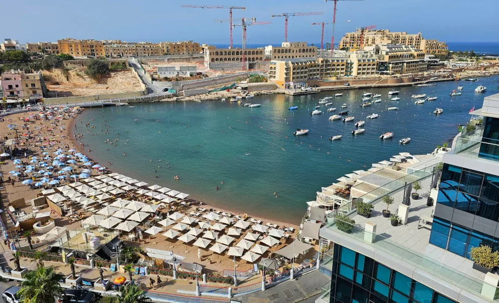 St George's Bay St Julian's Malta – spiaggia sabbiosa con acqua blu limpida fiancheggiata da hotel e ristoranti